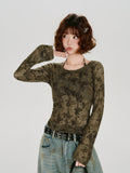 Woman posing with her hand on her chin, wearing the olive green geometric print mesh top and light wash jeans.