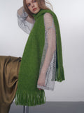 Model showcasing a green scarf with fringe detail over a mesh top