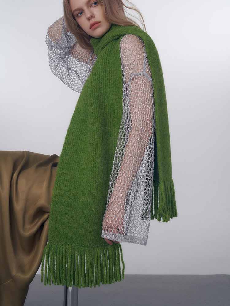 Model showcasing a green scarf with fringe detail over a mesh top
