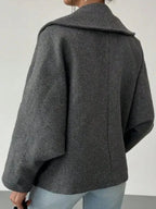 Back view of a woman in a grey wool blend cocoon coat with dropped shoulders.