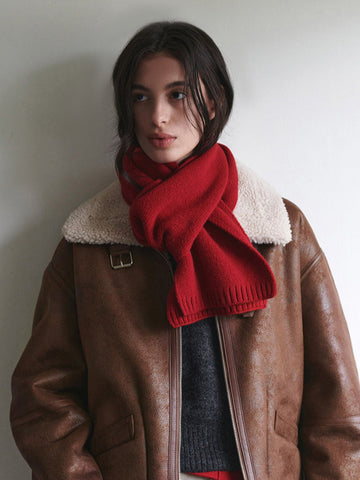 Woman wearing a red knit scarf and a brown aviator jacket
