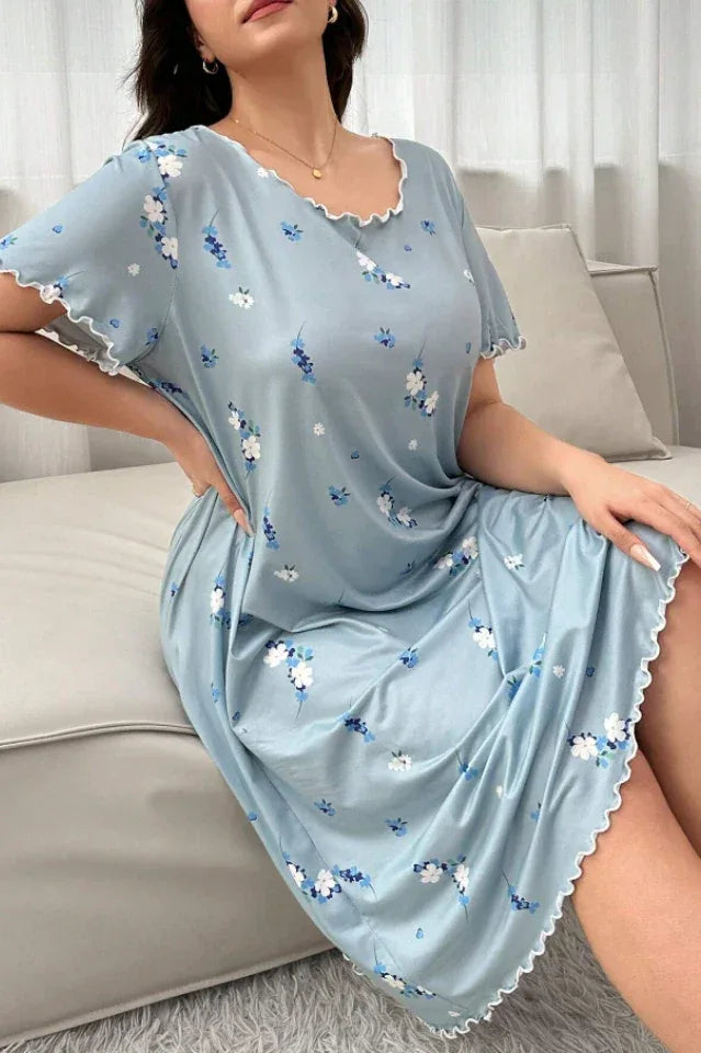 Woman wearing a light blue floral print nightgown sitting on a sofa. Main image