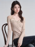Woman wearing a beige fitted ribbed knit cardigan with lace trim and button-down front while seated
