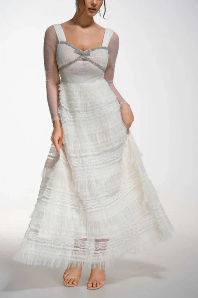 Woman wearing a white tiered tulle gown with sheer long sleeves and sparkling trim Main image