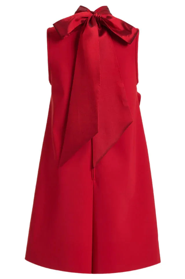 Close-up of the back of a red sleeveless A-line dress featuring a prominent satin bow at the neckline.