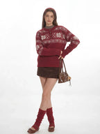 Woman wearing a red knit sweater with a white Fair Isle pattern and a button placket, posing with a handbag.