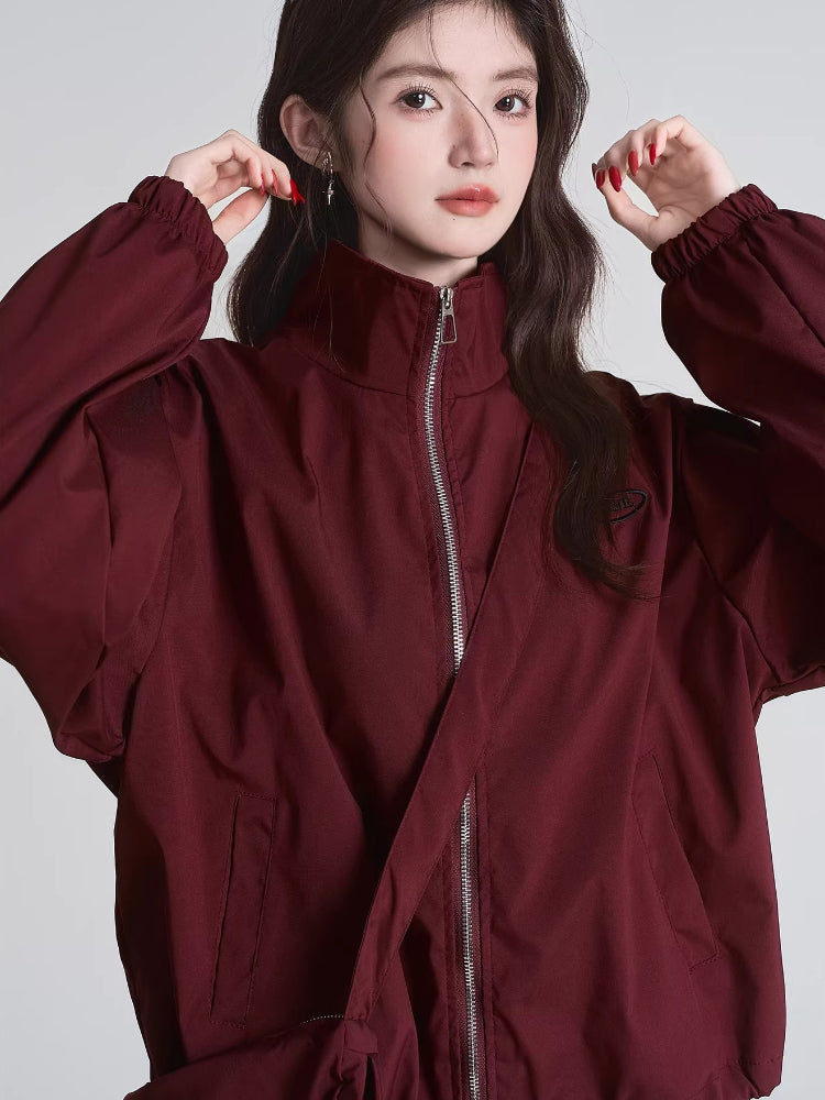Front view of a woman adjusting her maroon bomber jacket collar.