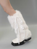White faux fur leg warmer with white ribbon ties on a person's leg, paired with white shoes.