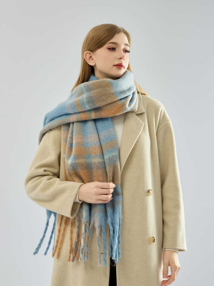 woman wearing a beige coat and a blue and tan plaid scarf with fringe