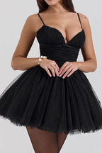 Close-up of a woman wearing a short black tulle dress with a ruched bodice.