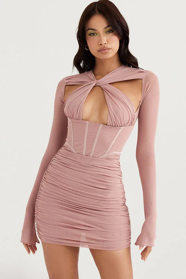 Woman wearing a dusty rose ruched bodycon dress with a twist-front cut-out neckline and long sleeves. Main image