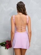 Back view of a woman in a lavender crepe sheath mini dress with an open back and criss-cross straps