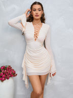 Woman wearing a cream ruched bodycon dress with lace-up neckline and flared sleeves