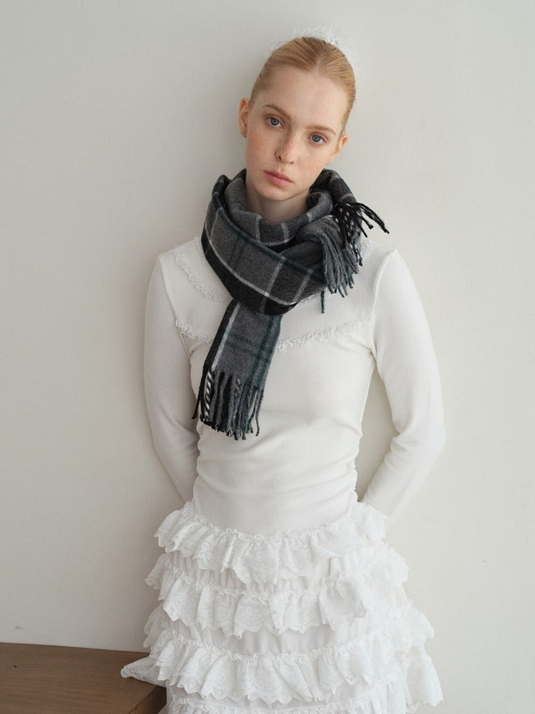 Woman wearing a white long-sleeve top, white pleated skirt, and grey polka dot tights, accessorized with a dark plaid scarf and silver boots.
