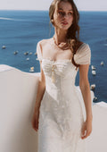Back view of a cream-colored jacquard midi dress with off-the-shoulder neckline and ruched detailing.