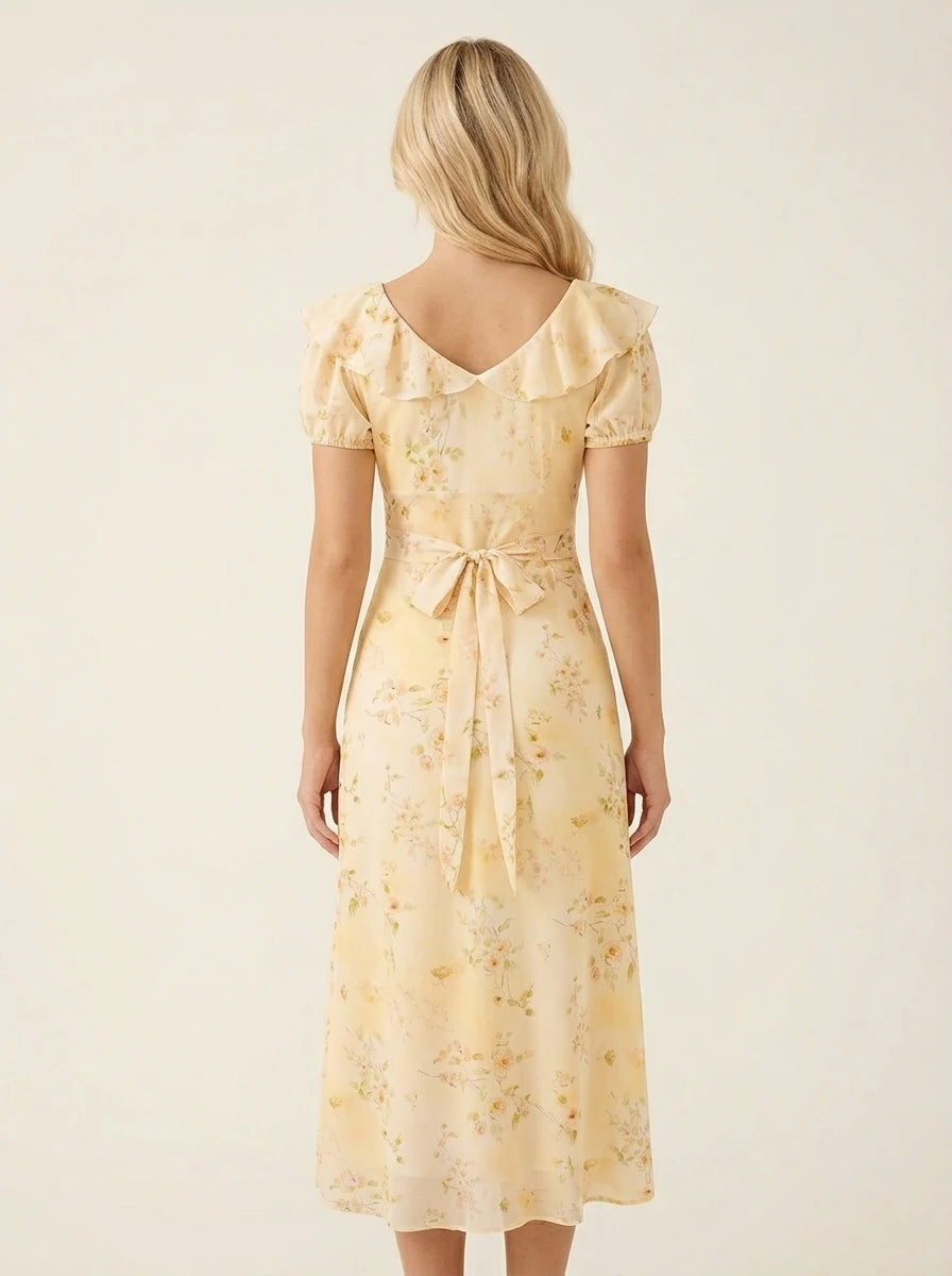 Back view of a woman in a yellow floral midi dress with a cinched waist and tie detail.