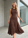 Woman walking outdoors wearing a brown polka dot sleeveless midi dress