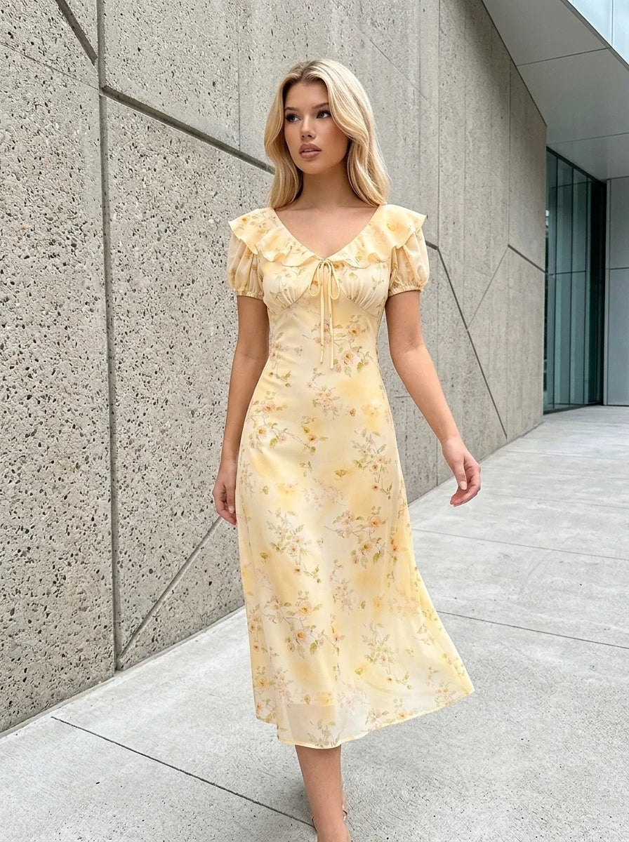 Woman walking outdoors in a yellow floral print midi dress with ruffled neckline and short sleeves.