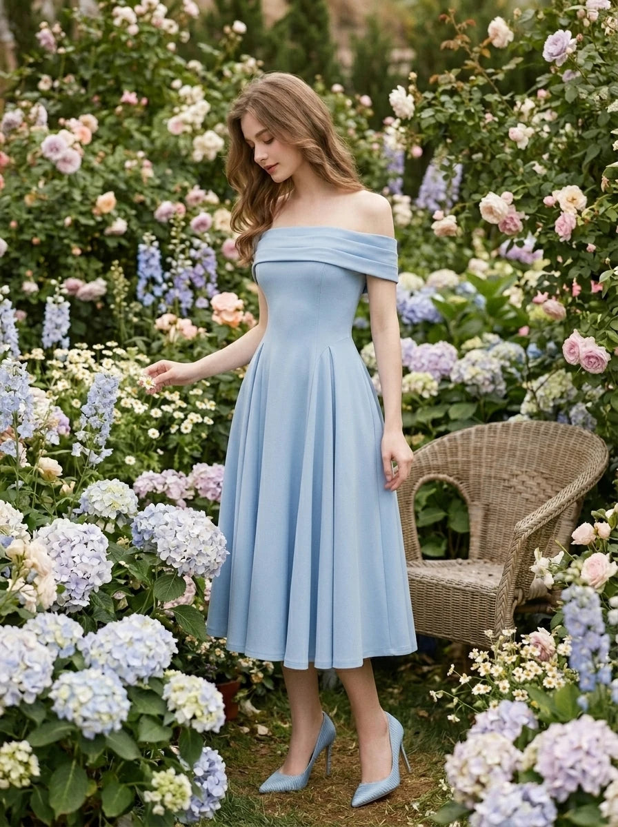 Woman in a light blue off-the-shoulder midi dress with a fitted bodice and full skirt, posing in a garden with flowers.