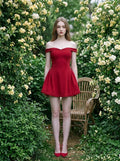 Woman in a red off-the-shoulder dress standing in a garden setting