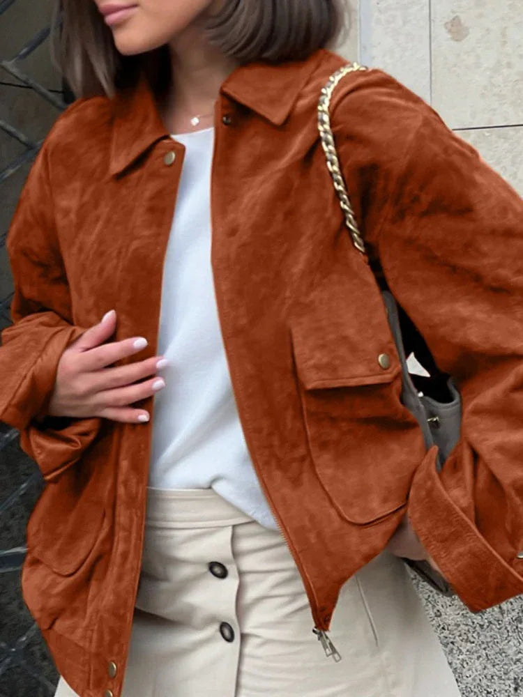 Woman adjusting the collar of her brown suede-like bomber jacket.