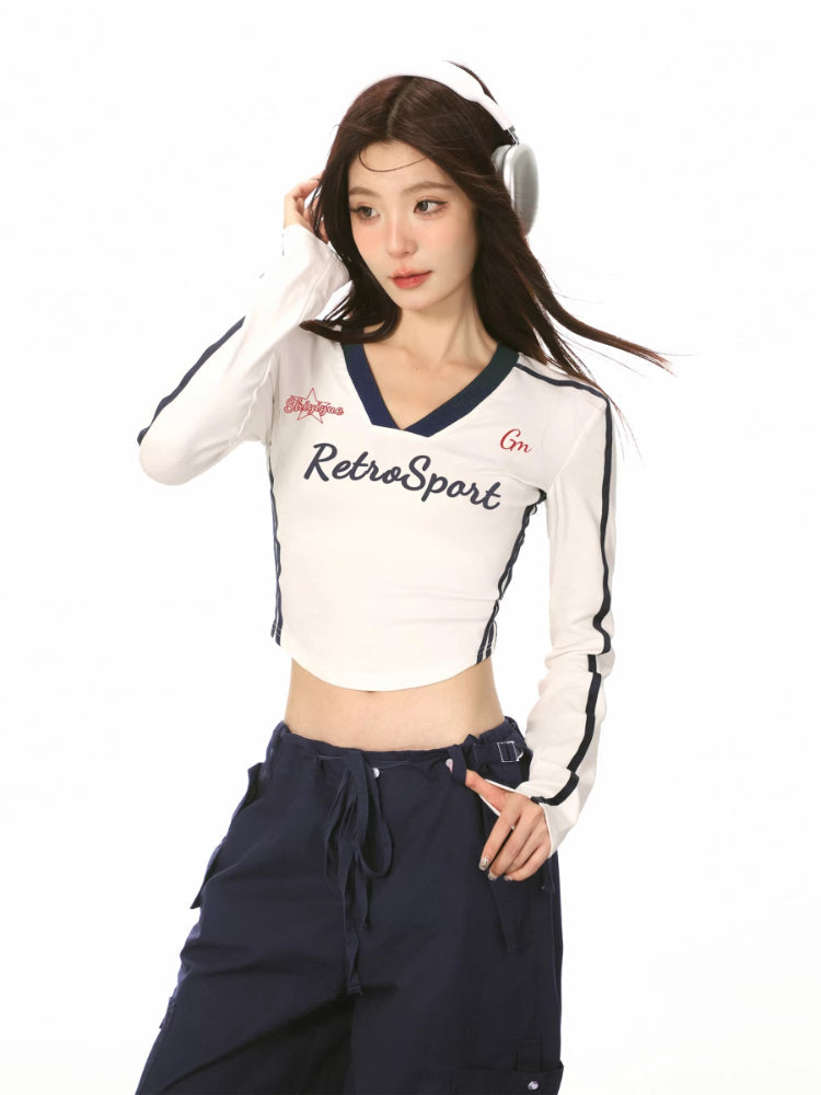 Model wearing a white long-sleeve crop top with 'RetroSport' graphic and navy trim.