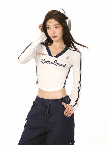Model wearing a white long-sleeve crop top with 'RetroSport' graphic and navy trim.