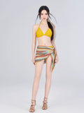 Woman wearing a yellow bikini with a colorful crochet knit wrap skirt