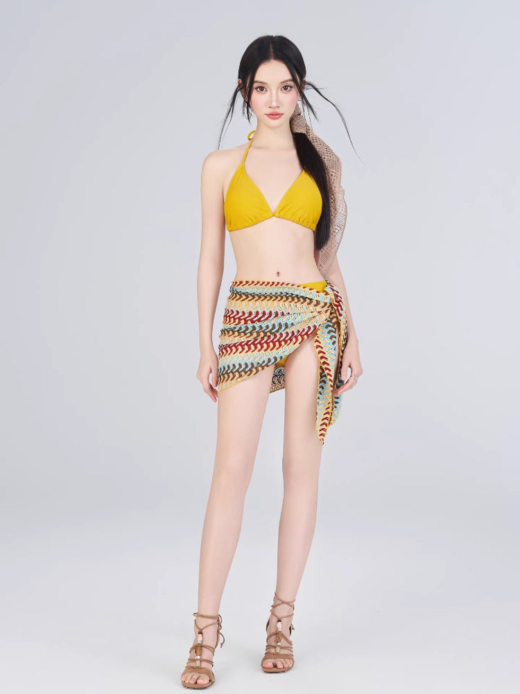 Woman wearing a yellow bikini with a colorful crochet knit wrap skirt