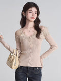 Woman wearing a beige fitted ribbed knit cardigan with lace trim and button-down front, holding a handbag