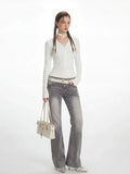 Full-length view of a woman in a white long-sleeve top and grey jeans
