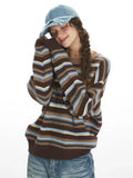 Woman in a striped knit sweater resting her head on her arm.