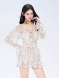 Front view of a woman posing in a white floral print mini dress with an off-the-shoulder neckline.