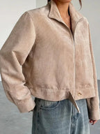 Close-up of the front of a beige corduroy cropped jacket on a woman.