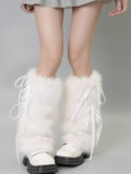 Full view of white faux fur leg warmers with ribbon ties on a person's legs, paired with white shoes.