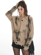 Close-up of the front of a tan knit cardigan with abstract black print.