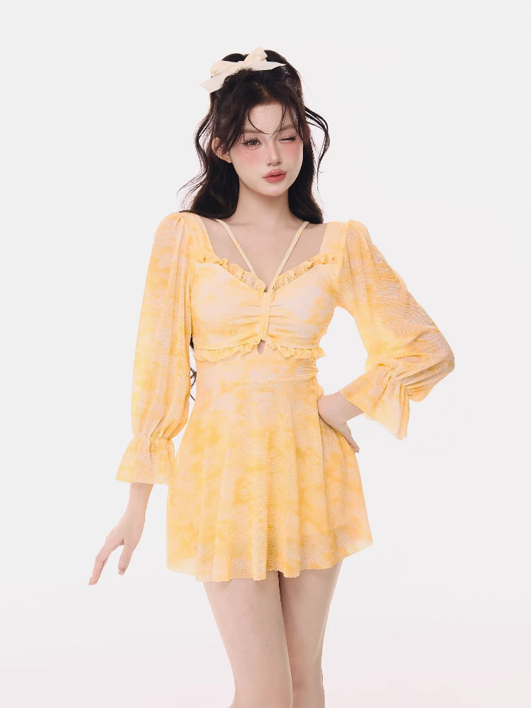 Woman wearing a yellow tie-dye mini dress with long puff sleeves and ruffled trim.