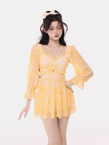 Woman wearing a yellow tie-dye mini dress with long puff sleeves and ruffled trim.