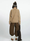 Back view of a woman in a tan knit sweater and wide-leg pants