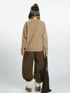 Back view of a woman in a tan knit sweater and wide-leg pants