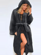 Woman wearing a long grey hooded faux fur coat with a belt