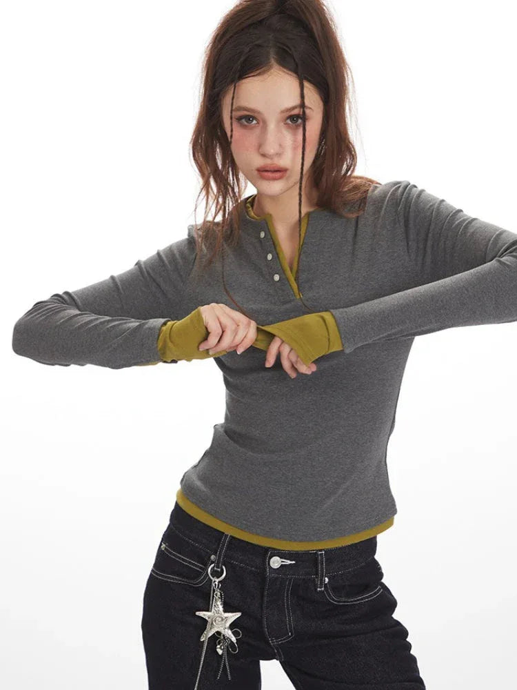 Woman adjusting the sleeve of a grey long-sleeve Henley top with contrast green cuffs and hem