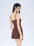 Rear view of a woman in a brown ribbed knit mini dress with spaghetti straps.