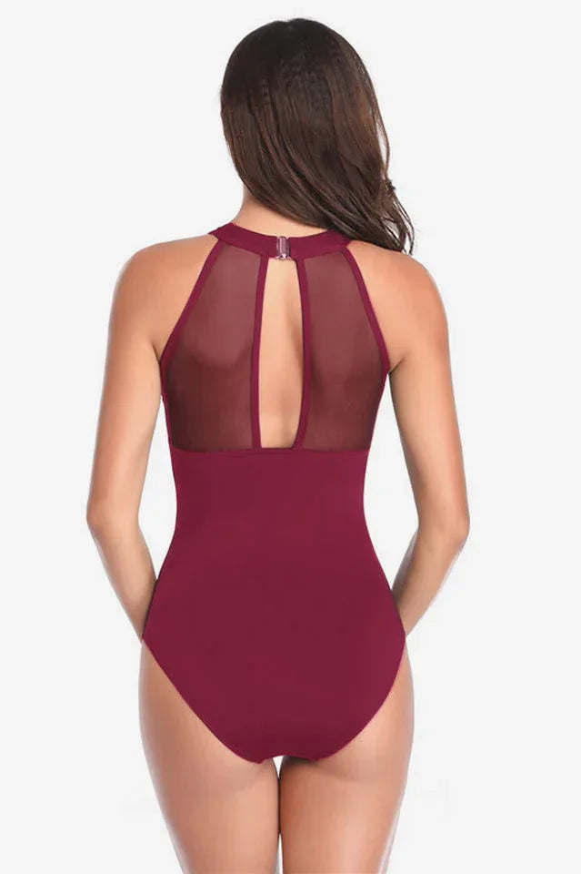 Rear view of a woman in a dark red halter neck one-piece swimsuit with mesh keyhole back