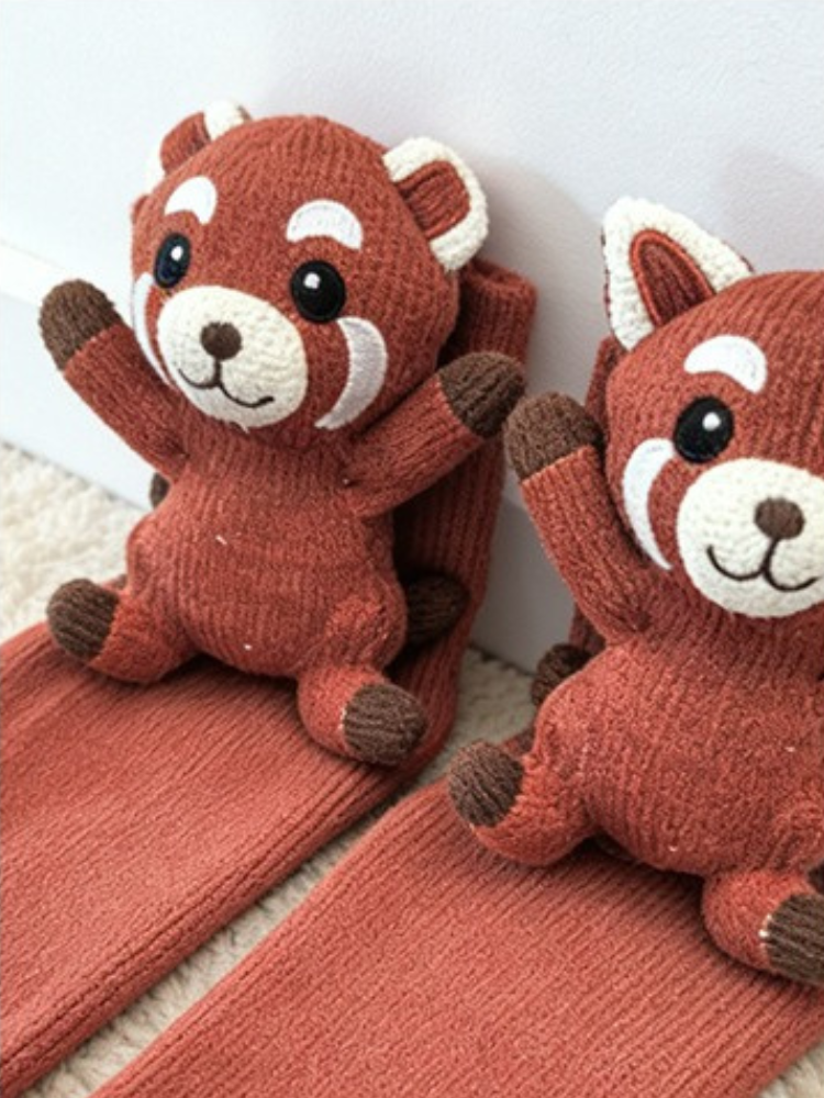 Close-up of two red knit crew socks, each featuring a red panda applique with embroidered facial features.