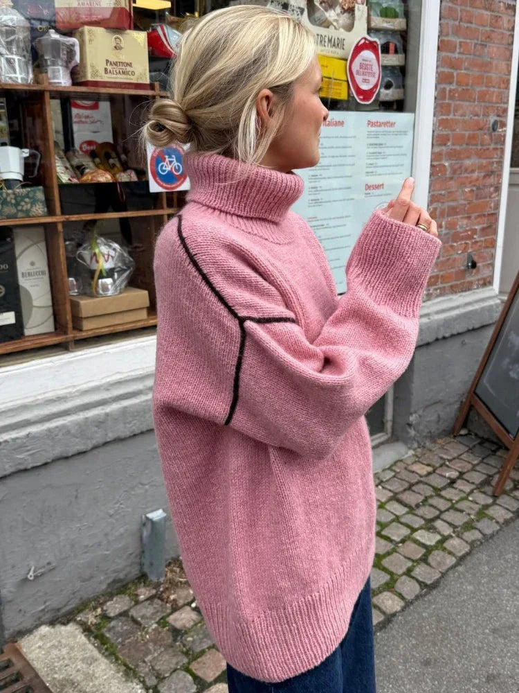 Woman in a pink oversized sweater with a turtleneck, standing outdoors