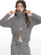 Woman adjusting the collar of a grey ribbed knit loungewear jacket, showing the zipper detail.