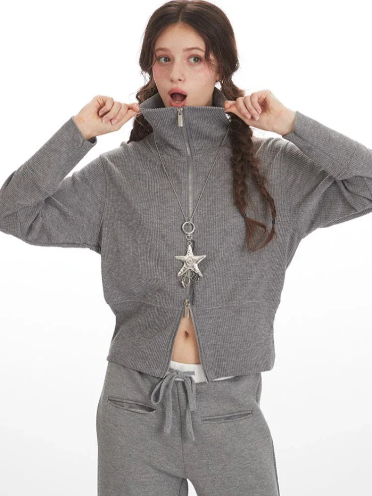 Woman adjusting the collar of a grey ribbed knit loungewear jacket, showing the zipper detail.