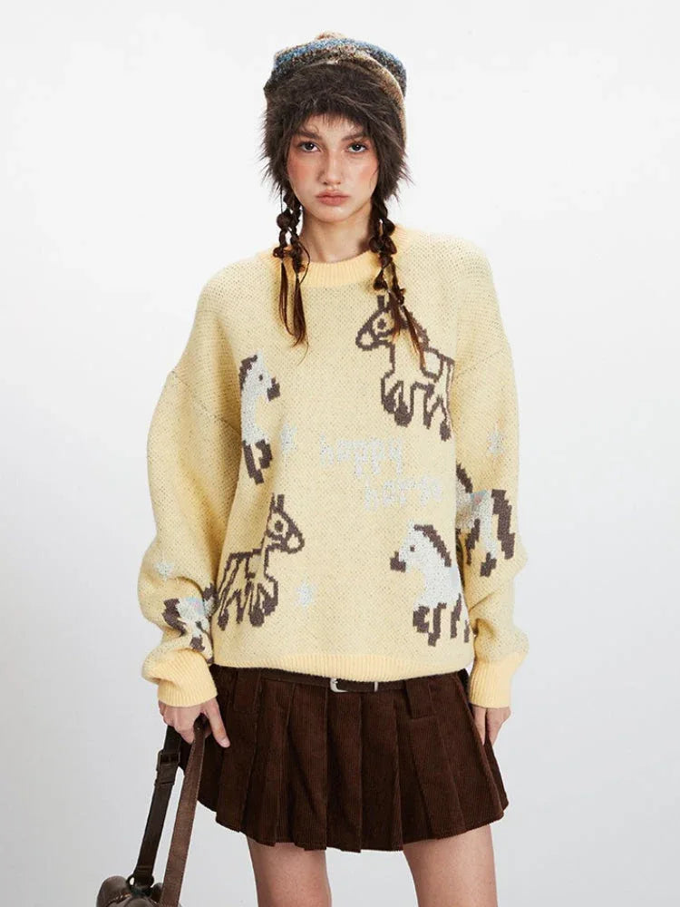 Close-up front view of a woman wearing a yellow knit sweater with a horse graphic print and a brown pleated skirt.