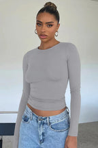 Woman in a grey long sleeve cropped top and blue jeans